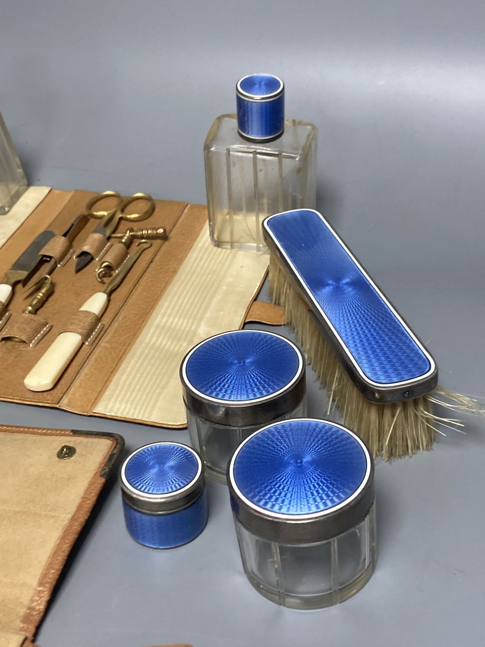 A late 19th/early 20th century French ten piece white metal and blue guilloche enamel travelling toilet set in leather case,